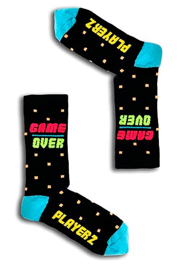 Caja de regalo con temática de videojuegos que muestra una silueta de mando de juego y las palabras "Game On", acompañada de calcetines negros con la inscripción "Player 1" y "Game Over" en colores neón.