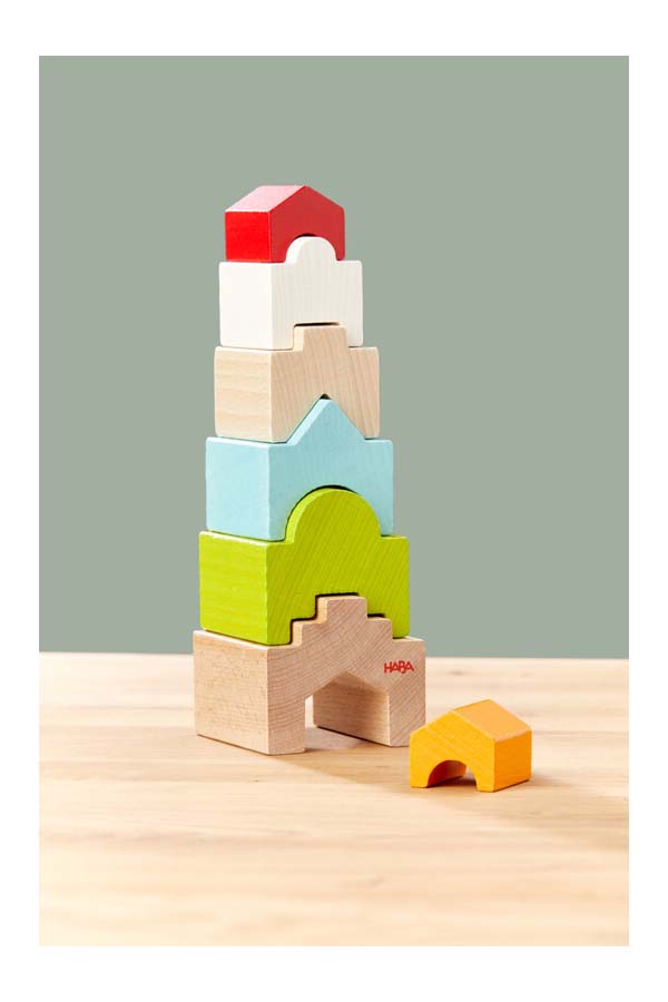 Una vista del juego "Torre de Casa" completamente apilado. Las piezas de madera, con colores vivos y formas de casas, invitan a los niños a desarrollar su creatividad y habilidades motoras.