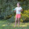 Una niña disfrutando del Juego Splash Water Catch de SES al aire libre. Un juego de lanzamiento y captura con pompones de agua ideal para los días de verano. Desarrolla la coordinación y garantiza risas sin fin.