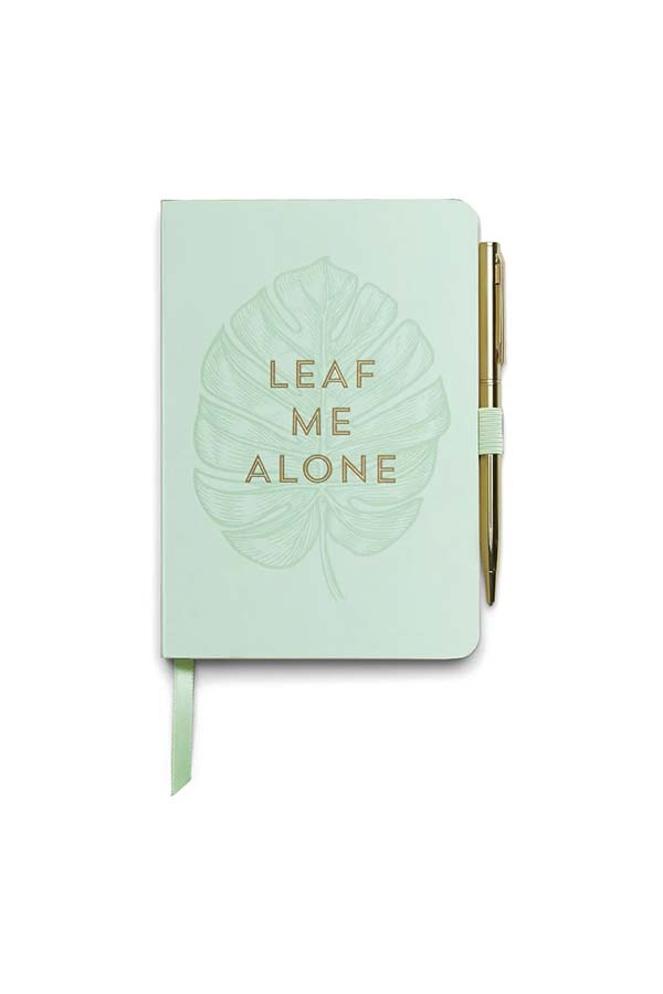 Un elegante cuaderno en color verde menta con la frase "Leaf Me Alone" en letras doradas sobre una ilustración de hoja tropical. Incluye un bolígrafo dorado sujeto con una banda elástica lateral y un marcador de página en cinta de raso.