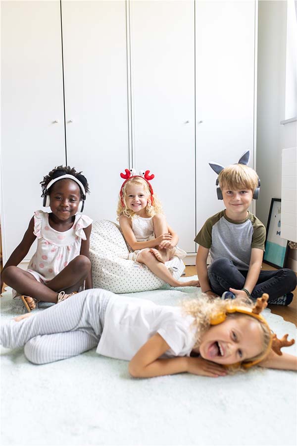 Grupo de niños usando auriculares Kidywolf con orejas intercambiables. Diversión asegurada con seguridad auditiva.