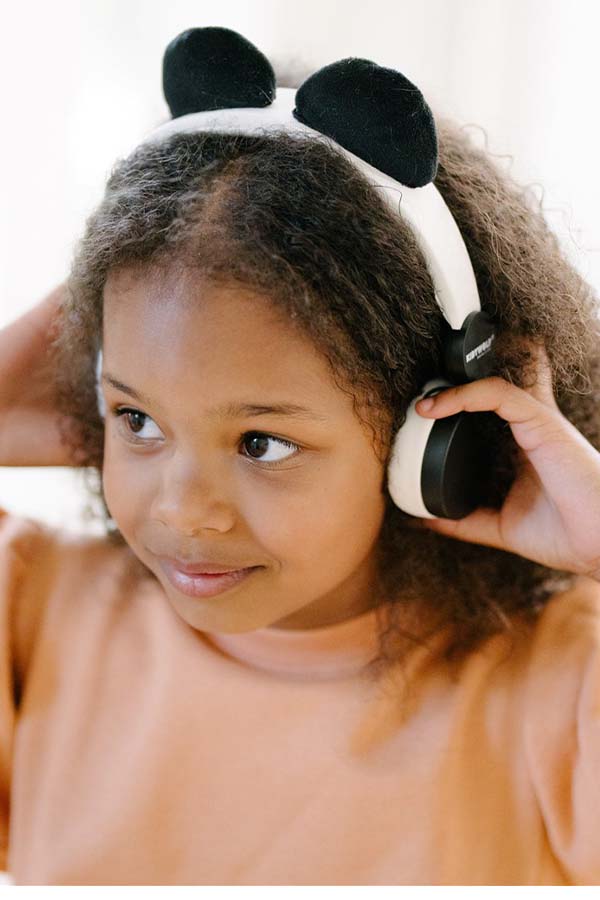 Niña disfrutando de su música con los auriculares panda de Kidywolf, ajustables y perfectos para niños.