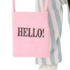 Detalle del pequeño bolso rosa que lleva Mia, con el mensaje “HELLO!”. Un accesorio con personalidad que complementa su look fresco y moderno.